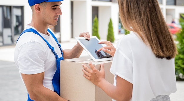 Young courier delivering goods to a young woman at home