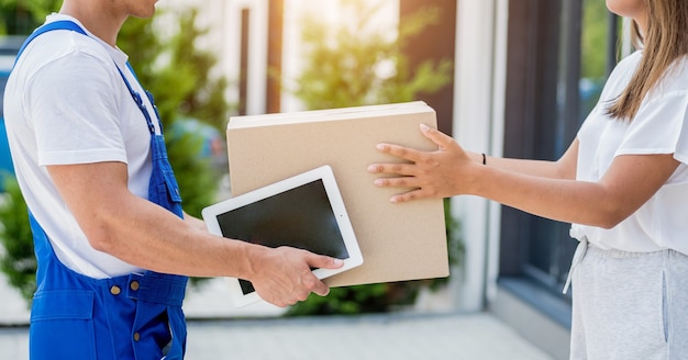 Young courier delivering goods to a young woman at home