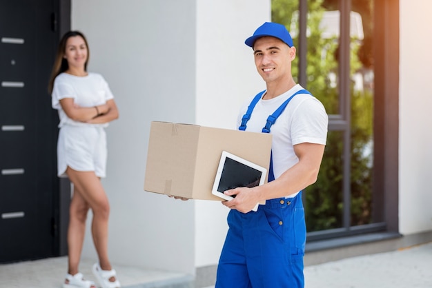 Young courier delivering goods to a young woman at home