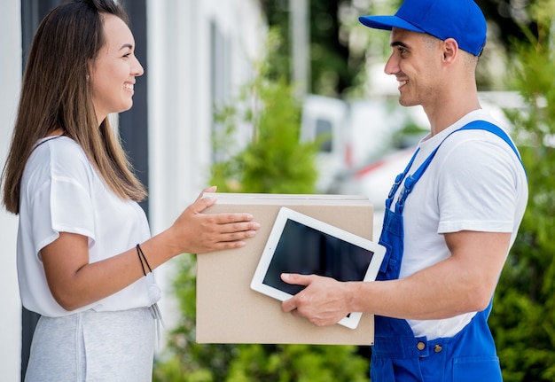 Young courier delivering goods to a young woman at home