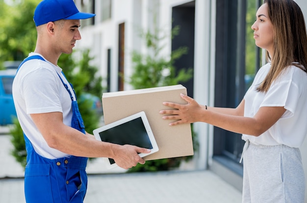 Young courier delivering goods to a young woman at home