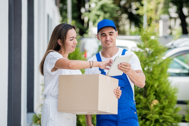 Young courier delivering goods to a young woman at home