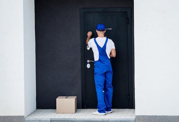 Young courier delivers goods to the door of the house.