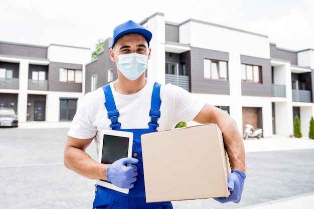 Young courier wearing a protective mask and gloves delivers goods during quarantine