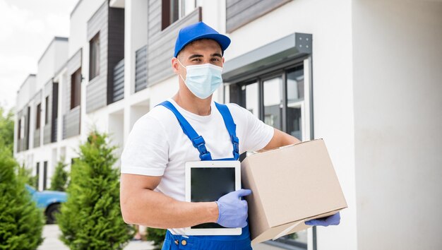 Young courier wearing a protective mask and gloves delivers goods during quarantine