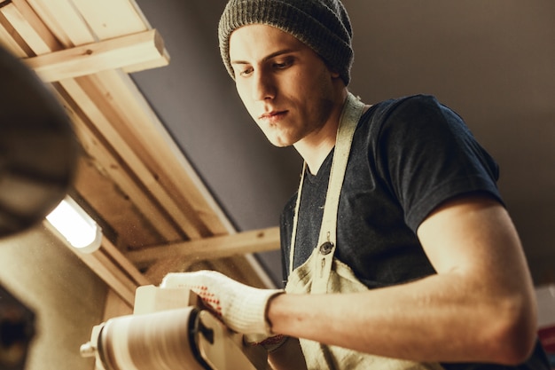 Photo young craftsman polishing plank in workshop