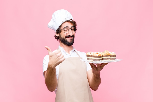 Young crazy baker man confectionery concept against pink wall