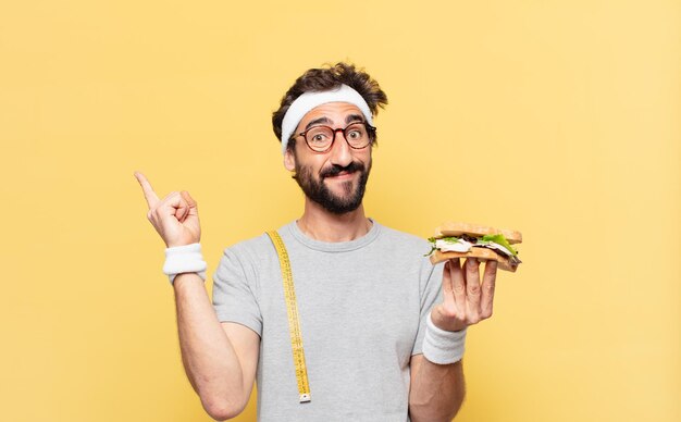 Young crazy bearded athlete celebrating successful a victory and holding a sandwich