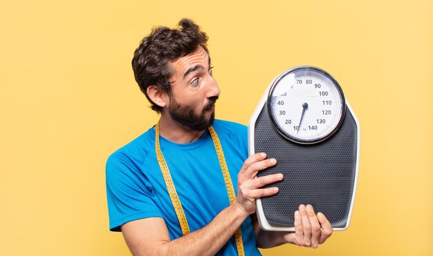 Young crazy bearded athlete scared expression and diet concept and holding a scale