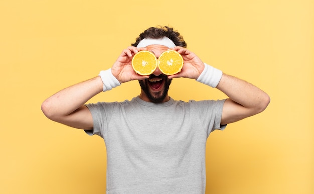 Young crazy bearded athlete surprised expression and an orange