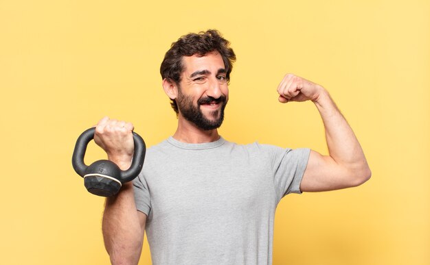 Young crazy bearded athlete with happy expression and holding a dumbbell