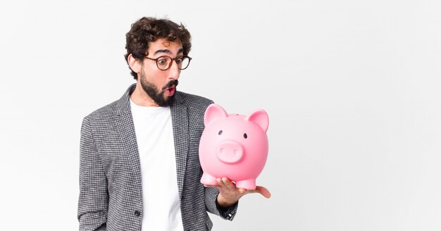 Young crazy bearded businessman with a piggy bank