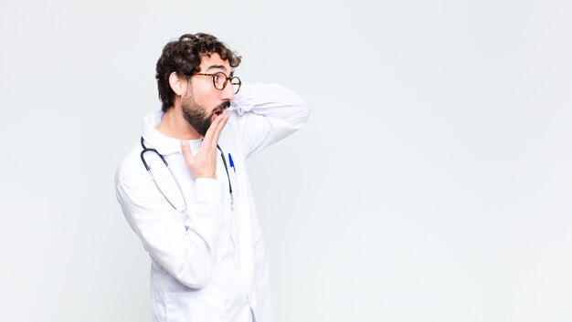 Young crazy bearded doctor man on copy space wall