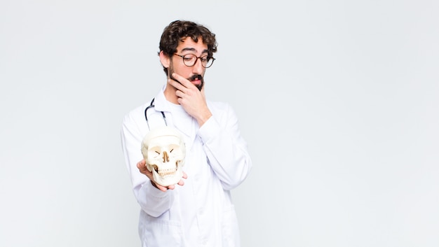 Young crazy bearded doctor man holding a human skull