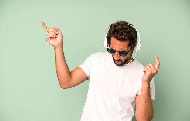 Young crazy bearded and expressive man listening music and\
dancing with headphones