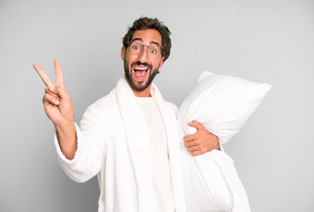 Young crazy bearded and expressive man wearing bathrobe and a pillow