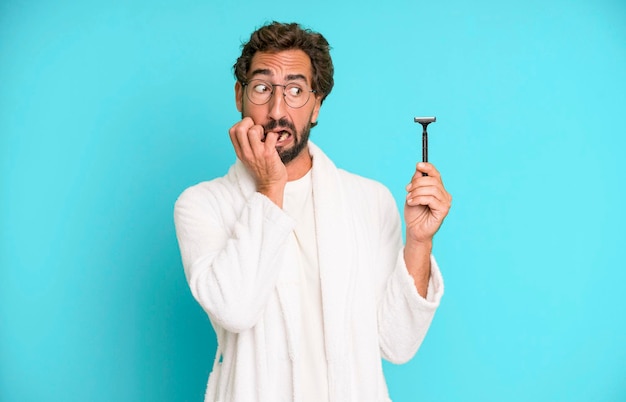 Young crazy bearded and expressive man wearing bathrobe and shaving beard concept