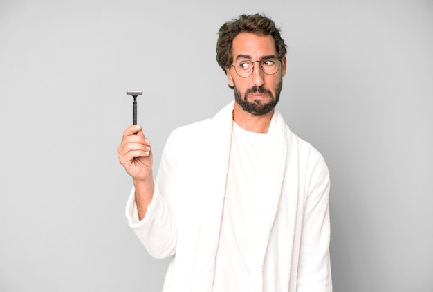 Young crazy bearded and expressive man wearing bathrobe and shaving beard concept