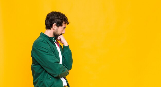 Young crazy bearded man against orange wall copy space.