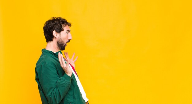 Young crazy bearded man against orange wall