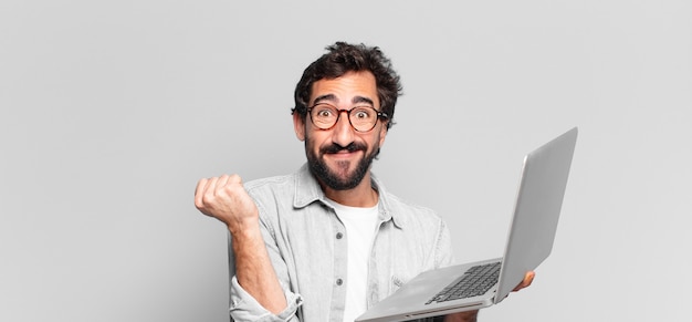 Young crazy bearded man. celebrating a triumph like a winner. laptop concept