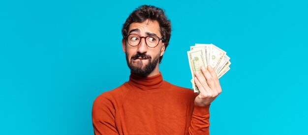 Photo young crazy bearded man confused expression. dollar banknotes concept