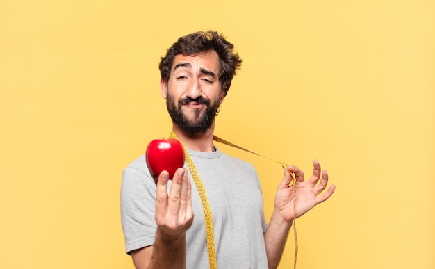 Young crazy bearded man dieting happy expression and holding an apple