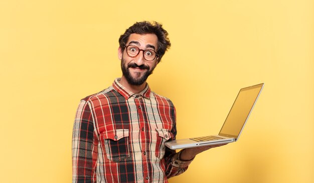 Young crazy bearded man happy expression and a laptop