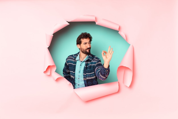 Young crazy bearded man. happy and surprised expression. paper hole empty background concept