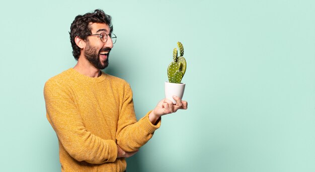 Young crazy bearded man holding a cactus house plant