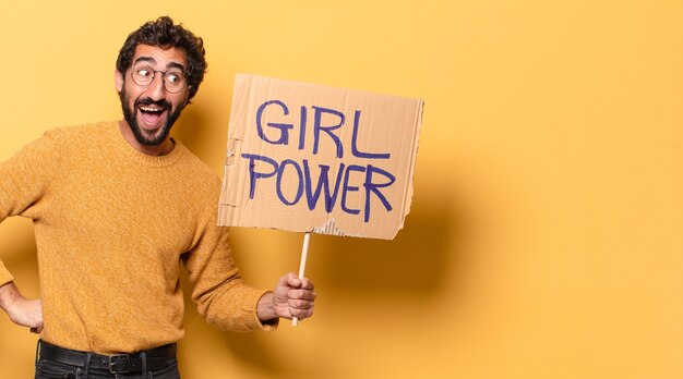 Young crazy bearded man holding a girl power banner