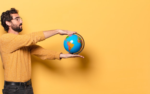 Young crazy bearded man holding a world globe map.