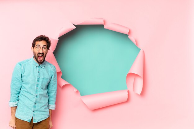 Young crazy bearded man near a paper hole