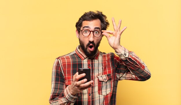 Young crazy bearded man scared expression and holding a phone