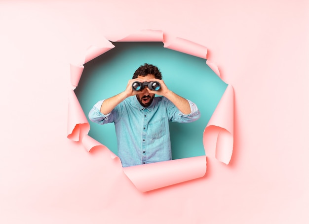 Photo young crazy bearded man. shocked or surprised expression. binoculars concept