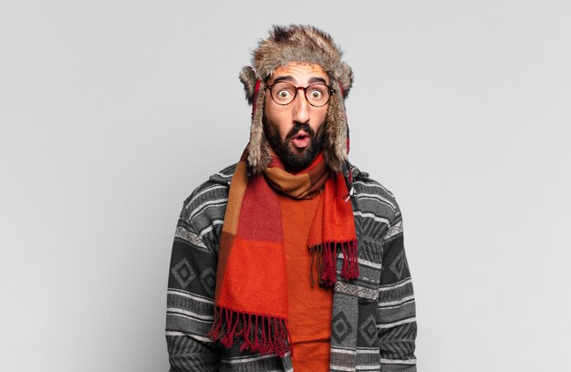 Young crazy bearded man. shocked or surprised expression and wearing winter clothes
