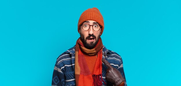 Young crazy bearded man. shocked or surprised expression and wearing winter clothes