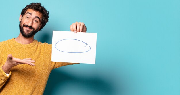 Young crazy bearded man showing a sheet of paper with a copy space