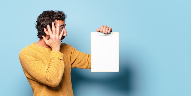 Young crazy bearded man showing a sheet of paper with a copy space