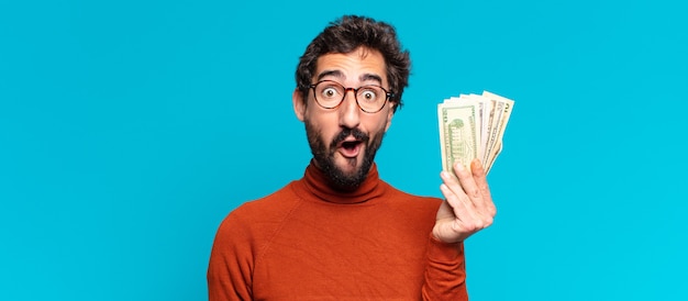Молодой сумасшедший бородатый мужчина удивлен выражением лица. доллар банкноты концепция