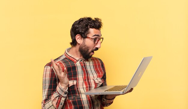 Young crazy bearded man surprised expression and a laptop