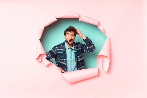 Young crazy bearded man. thinking or doubting expression. paper hole empty background concept