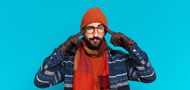 Photo young crazy bearded man. thinking or doubting expression and wearing winter clothes