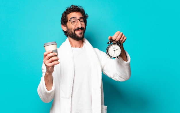 Young crazy bearded man wearing bathrobe and an alarm clock