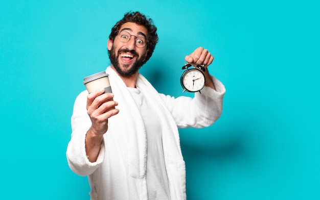 Young crazy bearded man wearing bathrobe and an alarm clock