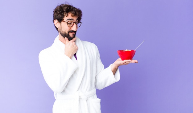 Young crazy bearded man  wearing bathrobe and holding a breakfast bowl