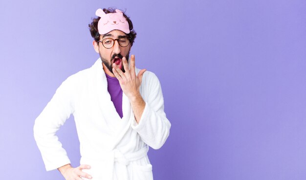 Young crazy bearded man wearing bathrobe and a sleep mask