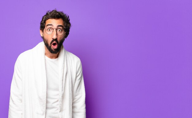 Young crazy bearded man wearing bathrobe and waking up at home