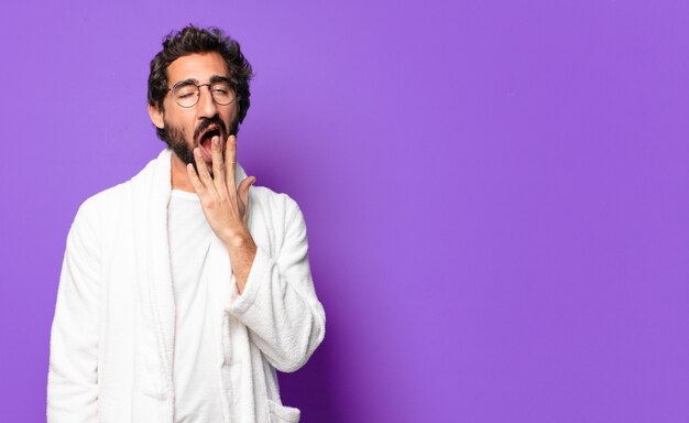 Young crazy bearded man wearing bathrobe and waking up at home