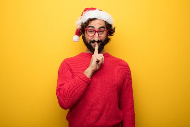 Young crazy bearded man wearing red glasses and santa claus hat 